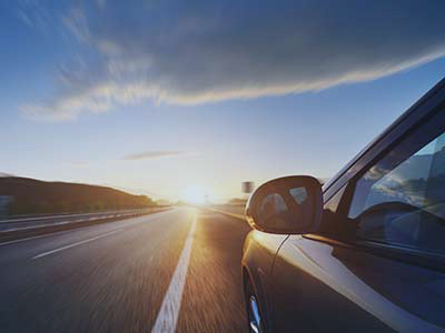 Car driving into sunset
